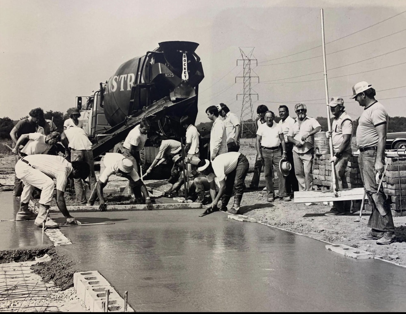 Crew finishing a road slab behind a Rocket concrete mixer
